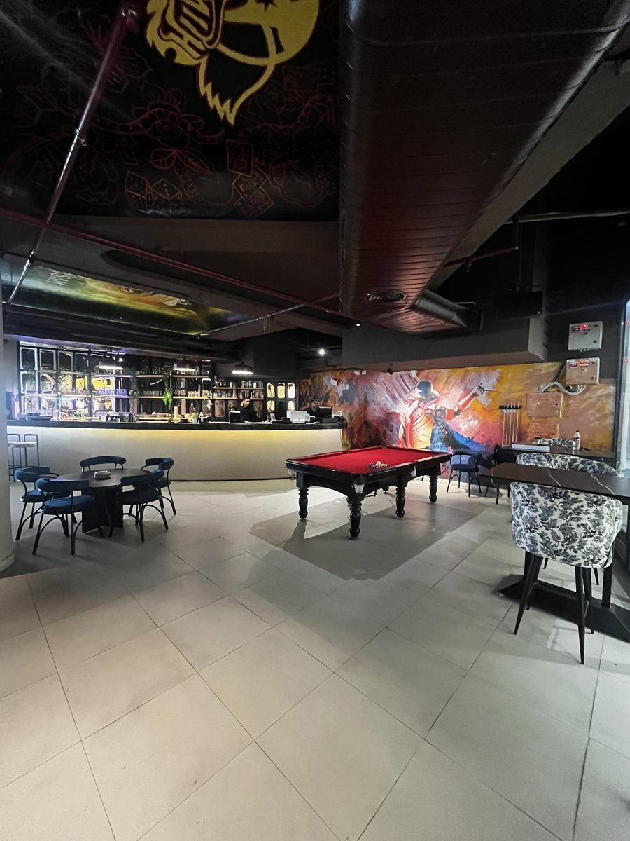 Pool table and bar area with wall murals at Tatsav Cafe